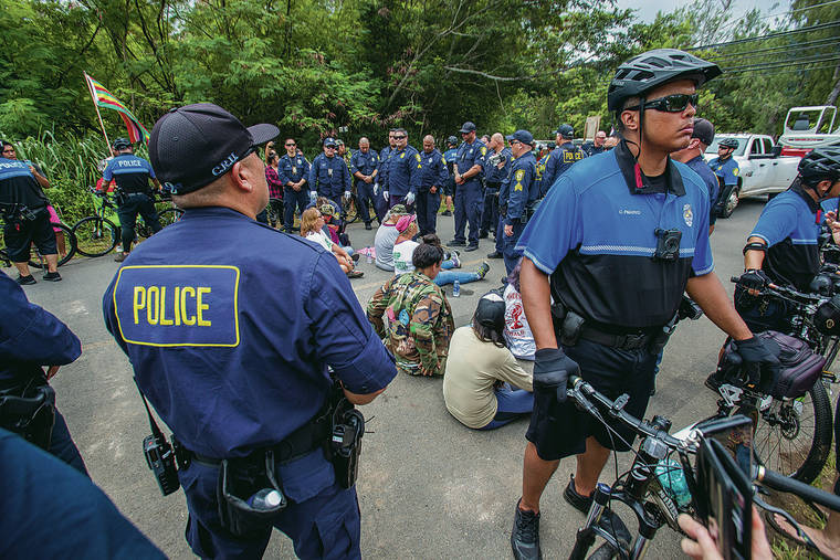 DENNIS ODA / DODA@STARADVERTISER.COM
                                Honolulu police Thursday surrounded the protesters and zip-tied their hands as they sat on the road. A construction vehicle was escorted into the park immediately afterward.
