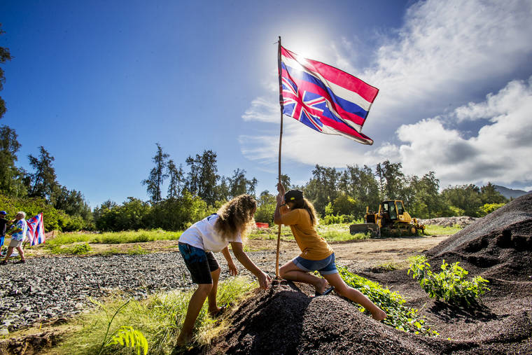 DENNIS ODA / DODA@STARADVERTISER.COM
                                Kahiwaliko Macomber, 11, and Bella Souki, 10, planting an upside down Hawaiian flag where the trees once stood in Sherwood Forest.