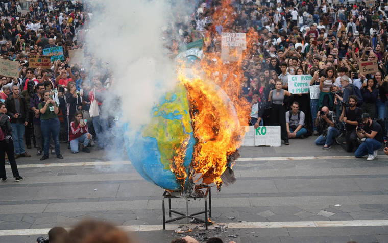 NICOLA MARFISI/ANSA VIA AP
                                Students set fire to a replica of the planet Earth during a worldwide protest demanding action on climate change, in Milan, northern Italy. The protests are inspired by Thunberg, who spoke to world leaders at a United Nations summit this week.