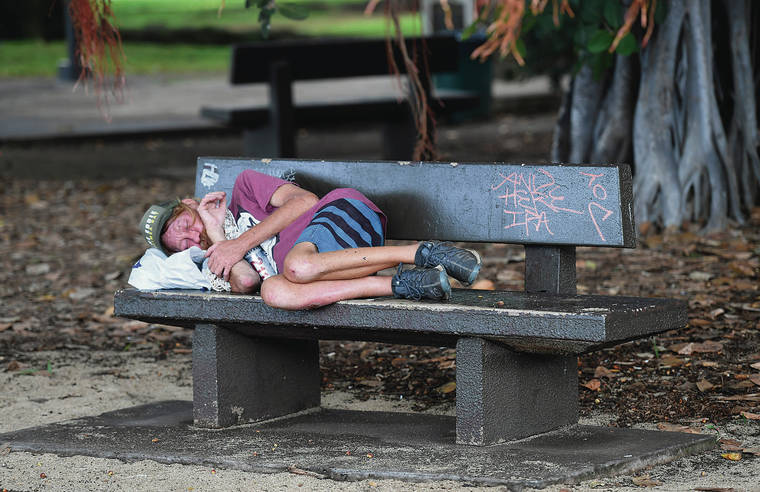 BRUCE ASATO / BASATO@STARADVERTISER.COM
                                A homeless man slept Monday on a bench in Waikiki fronting the Honolulu Zoo.