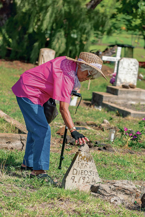 RON KOSEN / SPECIAL TO THE STAR-ADVERTISER
                                At the launch of a documentary about the Hanapepe Massacre of 1924 at the Filipino cemetery in Hanapepe, Kauai, Catherine Lo replaces a chip from a marker without a name dated the day of the massacre.