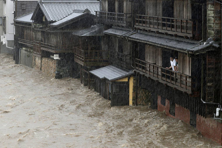 KYODO NEWS VIA AP
                                People watch the Isuzu River swollen by Typhoon Hagibis, in Ise, central Japan. Tokyo and surrounding areas braced for a powerful typhoon forecast as the worst in six decades, with streets and trains stations unusually quiet Saturday as rain poured over the city.