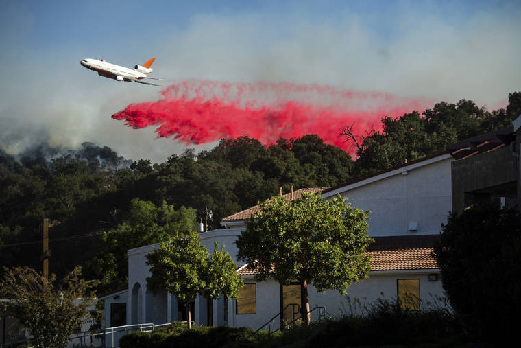 ASSOCIATED PRESS
                                An air tanker drops retardant behind the Newhall Church of the Nazarene while battling the Saddleridge Fire in Newhall, Calif., on Friday.