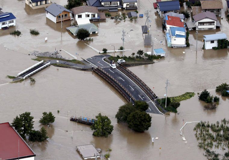 KYODO NEWS VIA AP
                                Cars are stranded on a road as the city is submerged in muddy waters after an embankment of the Chikuma River broke in Nagano, Japan.