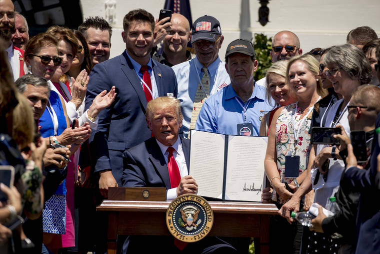 ASSOCIATED PRESS
                                Company representatives invited to the White House stand next to President Donald Trump as he holds up an executive order after he signs it during a Made in America showcase on the South Lawn in Washington on July 15.