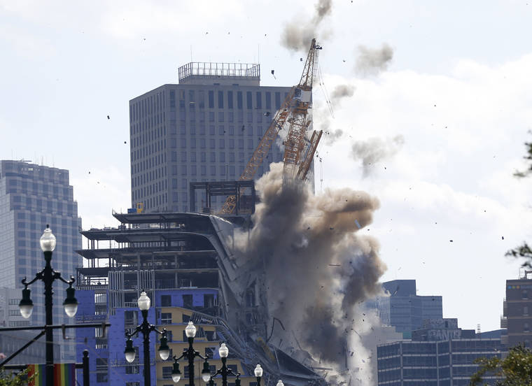 ASSOCIATED PRESS
                                Two large cranes from the Hard Rock Hotel construction collapse come crashing down after being detonated for implosion in New Orleans on Sunday.