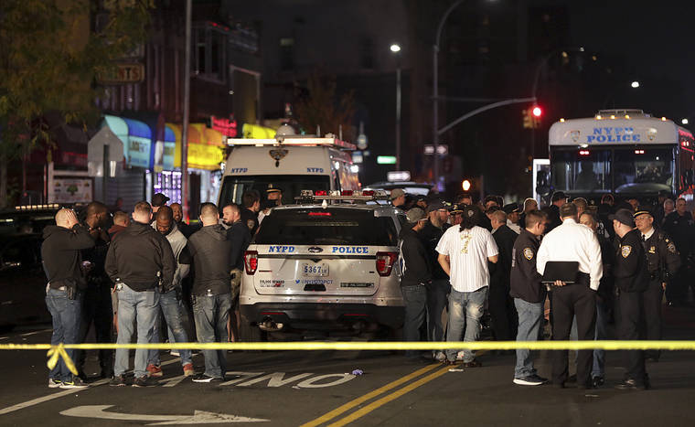 ASSOCIATED PRESS
                                New York Police and other emergency personnel investigate the scene of a shooting where two police officers were injured and one person was shot in the Brownsville neighborhood of the Brooklyn borough of New York.