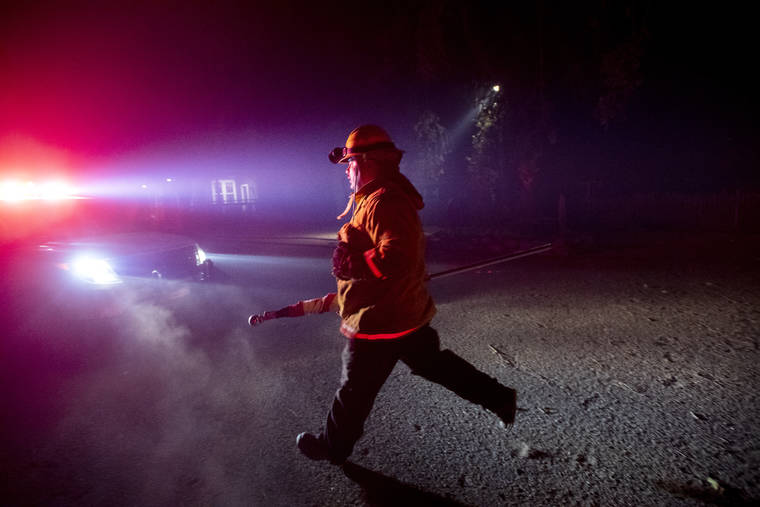 ASSOCIATED PRESS
                                A firefighter from Dry Creek Rancheria carries a flag he removed from a building as the Kincade Fire bears down on Healdsburg, Calif., on Sunday.