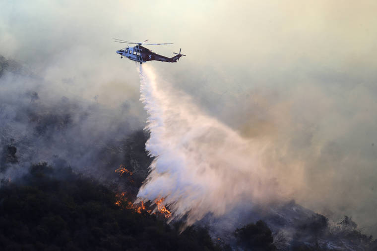 ASSOCIATED PRESS
                                A helicopter drops water as the Getty fire burns on Mandeville Canyon today.