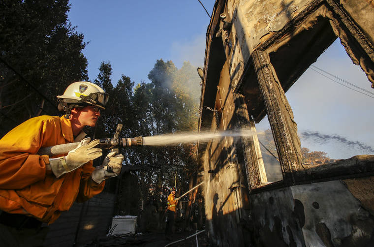 ASSOCIATED PRESS
                                Firefighters worked on a house destroyed by a wildfire called the Getty Fire in Los Angeles, Monday.