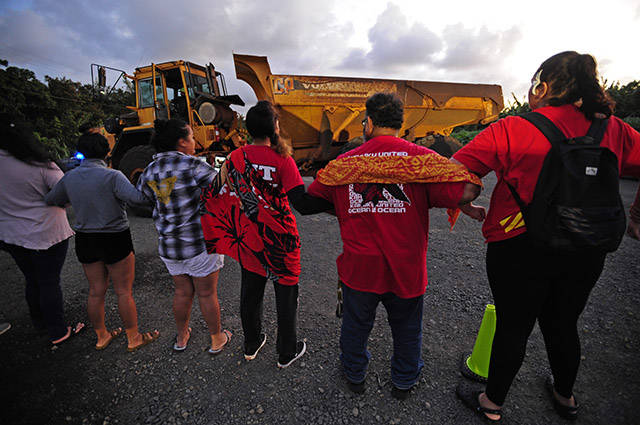 BRUCE ASATO / BASATO@STARADVERTISER.COM
                                Opponents of the Na Pua Makani wind farm project linked arms and stood their ground Monday as several pieces of heavy equipment and trucks were brought to the site of the protest off Kamehameha Highway, which some of the protesters felt was an aggressive move.
