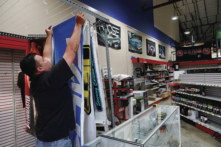 JAMM AQUINO / JAQUINO@STARADVERTISER.COM
                                John Takata, manager at Ron’s Performance auto store, on Thursday hung banners to be put up for sale. The auto parts store, a mainstay among performance and auto racing enthusiasts, will close its doors Oct. 31 after over 50 years in business.