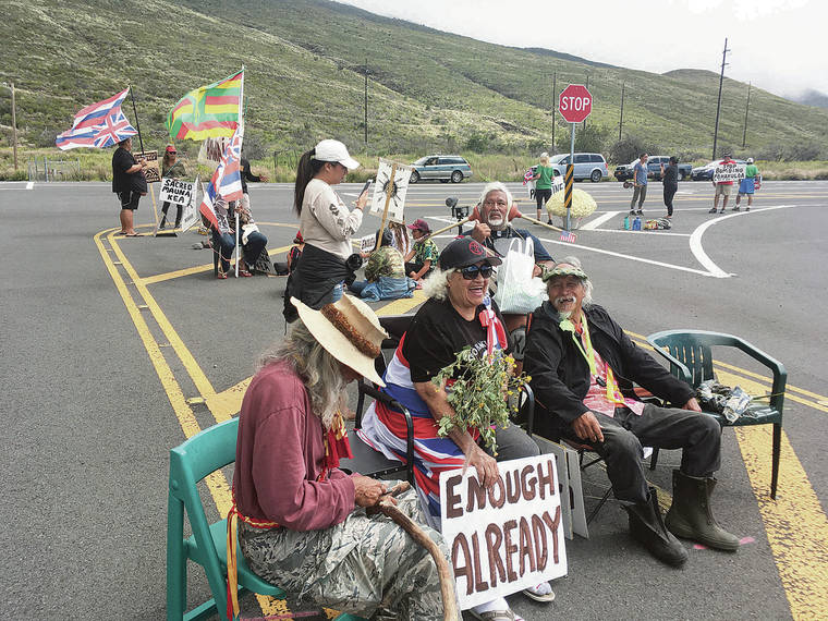 KEVIN DAYTON / KDAYTON@STARADVERTISER.COM Activists gathered at the main gate of the Pohakuloa Training Area on Wednesday. Mary “Auntie Maxine” Kahaulelio, 81, who held a sign, said the protest was an effort to stop desecration of the land.