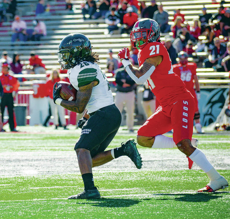 ANTHONY JACKSON / SPECIAL TO THE STAR-ADVERTISER
                                Hawaii running back Miles Reed, left, ran past New Mexico safety Brandon Burton during Saturday’s game at Dreamstyle Stadium in Albuquerque, N.M..