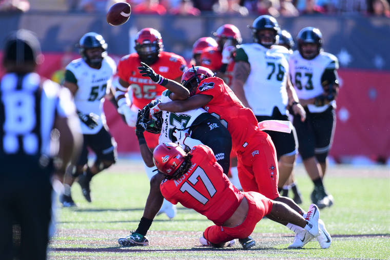 STEVEN ERLER / SPECIAL TO THE HONOLULU STAR-ADVERTISER Hawaii wide receiver Jared Smart (23) was hit after catching and fumbling the ball during the first half of a game between UNLV and Hawaii today at Sam Boyd Stadium in Las Vegas.