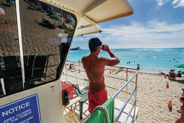 DENNIS ODA / 2018
                                Lifeguard Kainoa Lopes uses his binoculars to scan the ocean from a lifeguard tower near Dukes Restaurant at the Outrigger Waikiki Hotel.