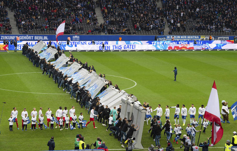 SOEREN STACHE/DPA VIA AP
                                Fans tear down a symbolic wall on the day of the 30th anniversary of the fall of the Berlin Wall prior the Bundesliga soccer match between Hertha BSC Berlin and RB Leipzig at the stadium in Berlin, Germany.