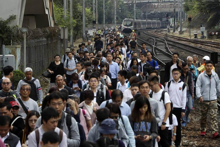 ASSOCIATED PRESS
                                Commuters walk on the railway after their train service is disrupted by pro-democracy protesters in Hong Kong.