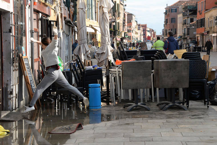 ASSOCIATED PRESS
                                A woman jumps over a puddle during cleaning following a flooding in Venice, Italy, today. The worst flooding in Venice in more than 50 years has prompted calls to better protect the historic city from rising sea levels as officials calculated hundreds of millions of euros in damage.