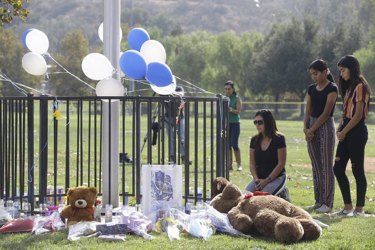 ASSOCIATED PRESS
                                Parent Mirna Herrera kneels with her daughters Liliana, 15, and Alexandra, 16 at the Central Park memorial for the Saugus High School victims in Santa Clarita, Calif., Friday.
