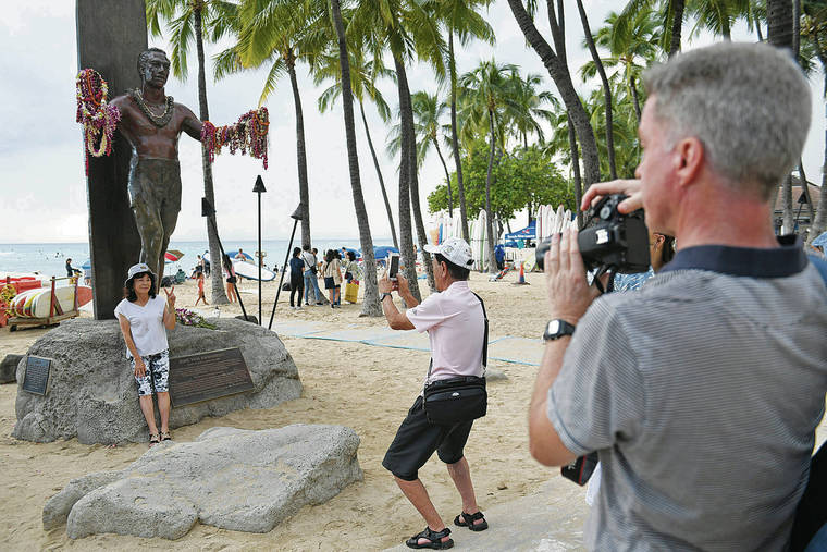 BRUCE ASATO / BASATO@STARADVERTISER.COM
                                Visitors stop to get photos of the Duke Kahanamoku statue on Waikiki Beach, Tuesday. Hawaii Tourism Authority is adding “responsible tourism” to its traditional branding.
