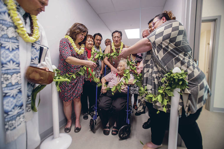 DENNIS ODA / DODA@STARADVERTISER.COM
                                Kahu Kordell Kekoa, left, officiated the blessing ceremony Thursday as the maile lei was untied for Janet Yamada and her son Neil Yamada, center.