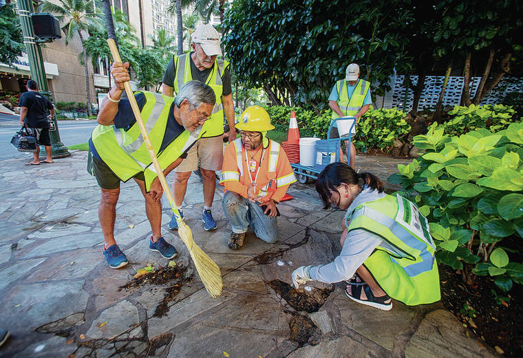 DENNIS ODA / DODA@STARADVERTISER.COM
                                City and County Community Relations Specialist Scott Goto, center, shows Jerry Taniyama, left, Andy Riley and Emma Ho how to repair the sidewalk so people don’t trip walking along Kuhio Avenue in Waikiki.