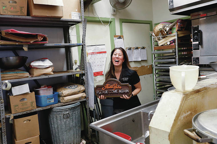 JAMM AQUINO / JAQUINO@STARADVERTISER.COM
                                Highway Inn owner Monica Toguchi holds a wooden sign inside the kitchen of Highway Inn restaurant on Monday in Waipahu. Highway Inn, known for their local and Hawaiian foods such as laulau and pipikaula, is closing after over 35 years at this location, and will re-open Dec. 30 at a new location in Waipahu.