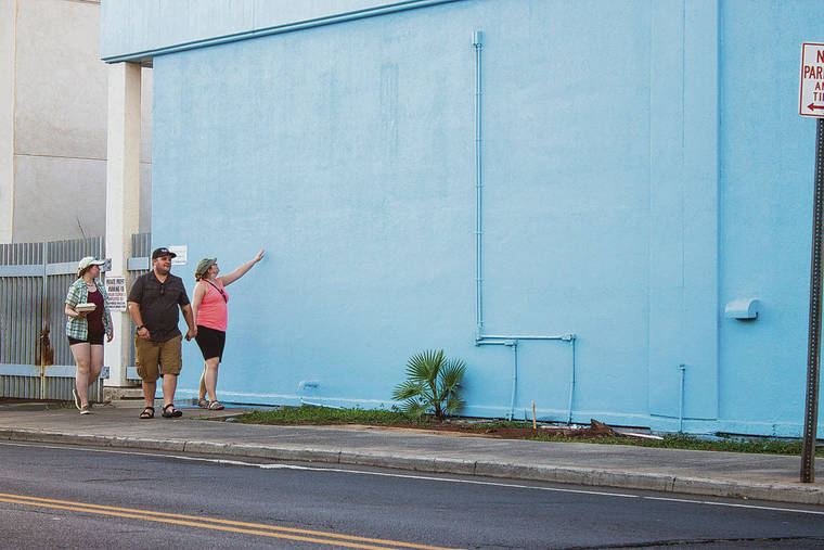 MEGAN MOSELEY / SPECIAL TO THE STAR-ADVERTISER
                                A group of tourists pause for a moment to evaluate a freshly painted Hawaiian Telcom wall off Dickenson Street in Lahaina where hours before a mural of a life-sized, female humpback whale, was seen.