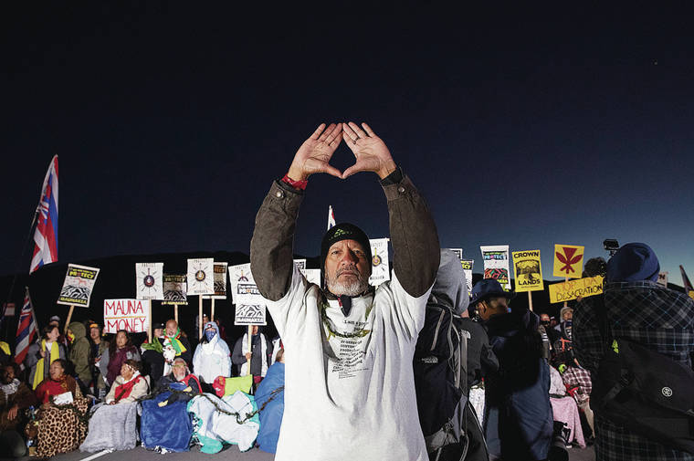 CINDY ELLEN RUSSELL / CRUSSELL@STARADVERTISER.COM
                                Dexter Kaiama held his hands high as a tribute to Mauna Kea before a line of kupuna who formed a human barricade early in the morning to stop the construction of the Thirty Millimeter Telescope on July 15.