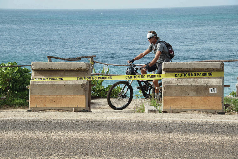 CRAIG T. KOJIMA /CKOJIMA@STARADVERTISER.COM
                                A biker made his way Monday on a path between the beach and barricades on Kamehameha Highway at Sunset Beach.