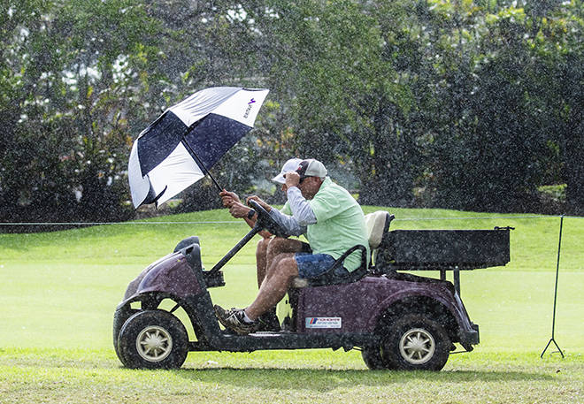 CINDY ELLEN RUSSELL / CRUSSELL@STARADVERTISER.COM
                                Sony Open volunteers braced against the rain with an umbrella as they drove a cart during the second round of the Sony Open at the Waialae Country Club today.