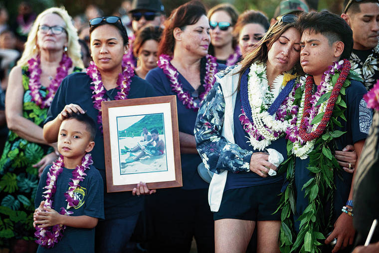 KAT WADE / SPECIAL TO THE STAR-ADVERTISER
                                Kaulike Kalama’s wife, Kaohi, second from right, and son Kaumana were surrounded by family including sister-in-law Cassie Segovia, left, who was holding a photo of Kalama and his son.