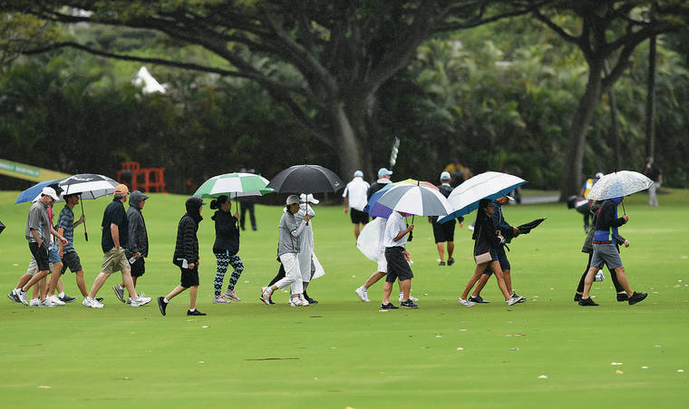 BRUCE ASATO / BASATO@STARADVERTISER.COM
                                While rain soaked the islands over the weekend, Hawaii island endured most of the rainfall. Spectators made their way across the first fairway during the final round of the Sony Open in Hawaii on Sunday at the Waialae Country Club.