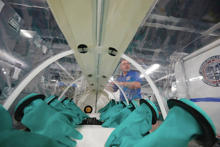 JAMM AQUINO / JAQUINO@STARADVERTISER.COM                                Chris Crabtree, executive director of the Hawaii Healthcare Emergency Management Coalition, handles an isolation pod used for the treatment of infected patients.
