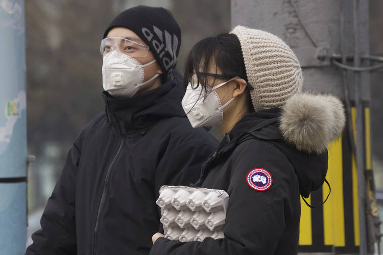 ASSOCIATED PRESS
                                Residents wearing masks waited at a traffic light in Beijing, China.