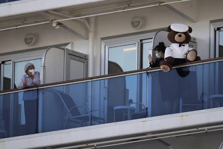 ASSOCIATED PRESS
                                A woman with a teddy bear waved to another passenger quarantined on the Diamond Princess cruise ship, Feb. 11, in Yokohama, near Tokyo. Life on board the luxury cruise ship, which has dozens of cases of a new virus, can include fear, excitement and soul-crushing boredom, according to interviews by The Associated Press with passengers and a stream of tweets and YouTube videos.