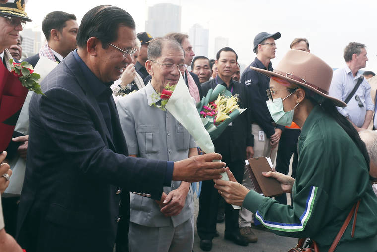 ASSOCIATED PRESS
                                Cambodia’s Prime Minister Hun Sen, left, gives a bouquet of flowers to a passenger who disembarked from the MS Westerdam, owned by Holland America Line, at the port of Sihanoukville, Cambodia, Friday. Hundreds of cruise ship passengers long stranded at sea by virus fears cheered as they finally disembarked and were welcomed to Cambodia.