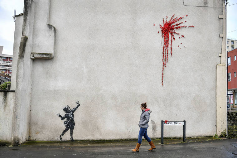 ASSOCIATED PRESS
                                A woman walks past a new artwork on the side of a house in Bristol, England, on Feb. 13, which has been confirmed as the work of street artist Banksy.