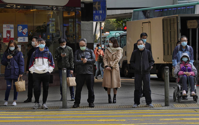 ASSOCIATED PRESS
                                People wearing face masks stand at a downtown street in Hong Kong on Monday.