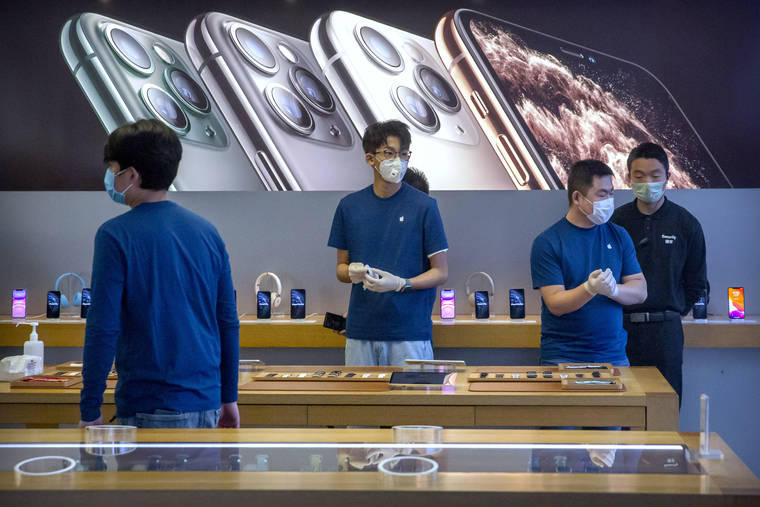 ASSOCIATED PRESS                                Employees wear face masks as they stand in a reopened Apple Store in Beijing on Feb. 14. Apple Inc. is warning investors that it won’t meet its second-quarter financial guidance because the viral outbreak in China has cut production of iPhones.