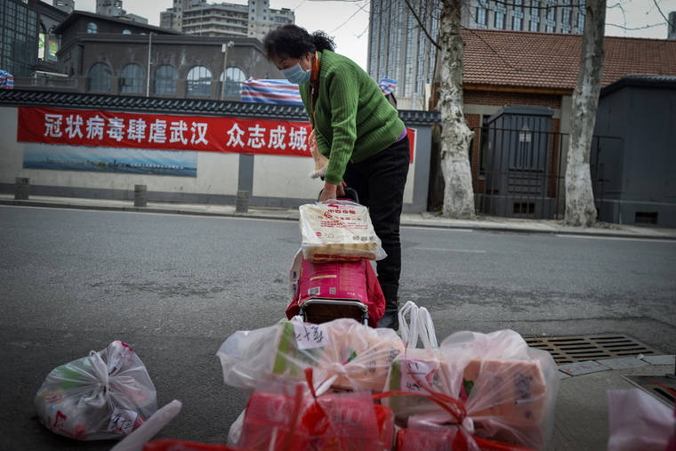 ASSOCIATED PRESS
                                A woman uses a trolley bag to collect foods distributed by volunteers outside her home in Wuhan in central China’s Hubei province on Saturday. South Korea and China both reported a rise in new virus cases as the South Korean prime minister warned that the fast-spreading outbreak linked to a local church and a hospital in the country’s southeast had entered a “more grave stage.”