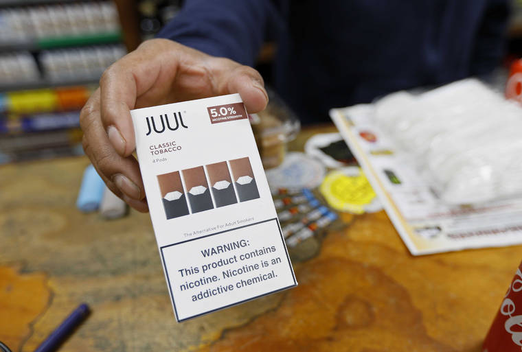 ASSOCIATED PRESS
                                A cashier displayed a packet of tobacco-flavored Juul pods, in June 2019, at a store in San Francisco. Investigators from 39 states will look into the marketing and sales of vaping products by Juul Labs, including whether the company targeted youths and made misleading claims about nicotine content in its devices, officials announced today.