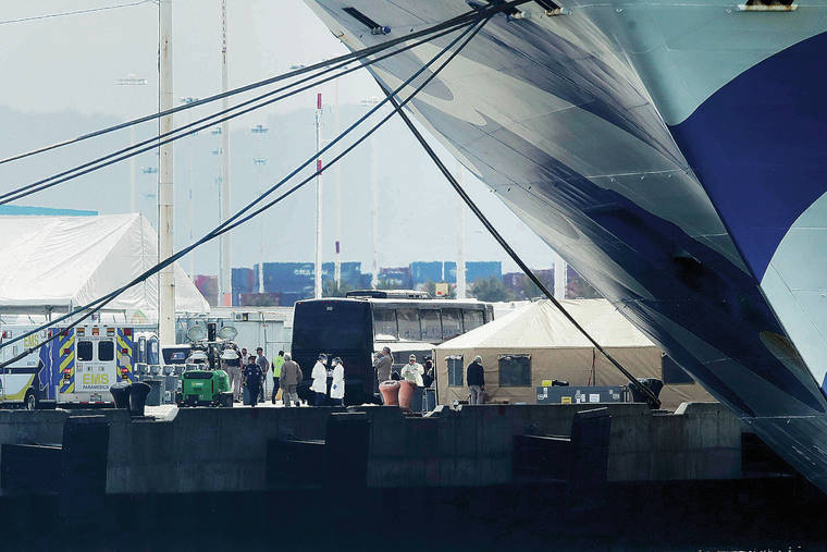 ASSOCIATED PRESS
                                People waited Monday below the Grand Princess to assist passengers as they disembarked. The cruise ship, which was carrying multiple people who have tested positive for COVID-19, finally docked at the Port of Oakland in California.
