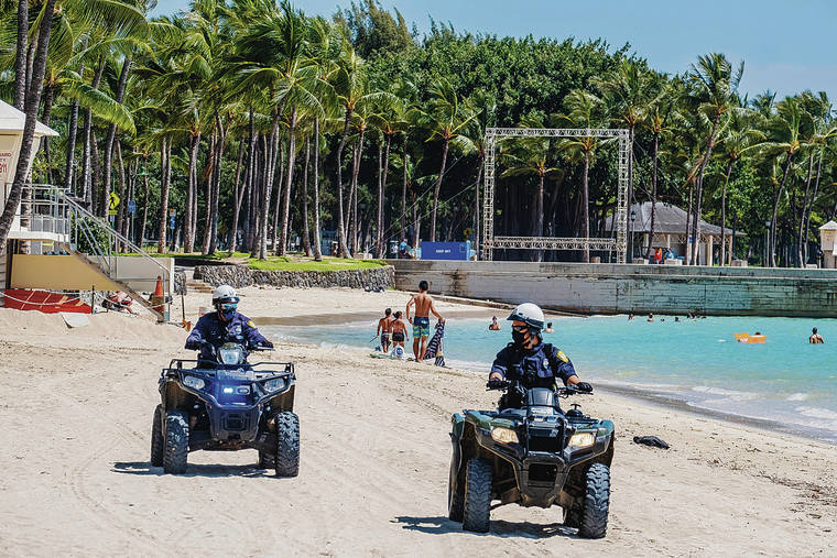 DENNIS ODA / DODA@STARADVERTISER.COM
                                Police patrolled the beaches in Waikiki to warn people if they were breaking the law. Many beachgoers were wearing face masks.