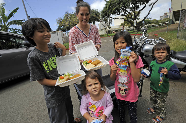BRUCE ASATO / MARCH 23
                                Ruth Iaela-Pukahi, standing in back, shows two of the 7 school meals she picked up for her 7 students and youngsters. School meals were available free for children up through age 18 regardless of eligibility for subsidized lunch.