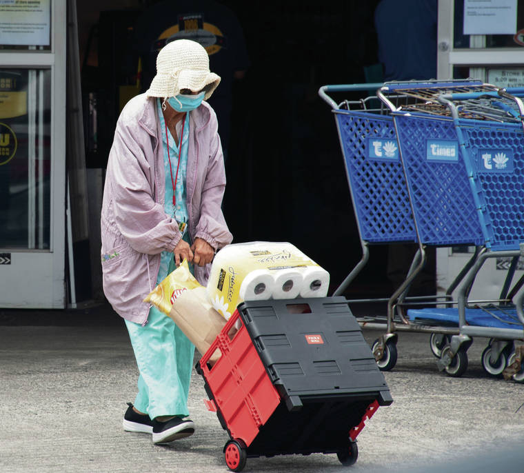 CRAIG T. KOJIMA / CKOJIMA@STARADVERTISER.COM
                                A shopper wore a mask and was well covered Friday after exiting Times Supermarket on Beretania Street. The latest fatality was an elderly Oahu resident who was hospitalized after returning from Washington state.
