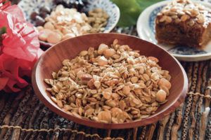 CRAIG T. KOJIMA / CKOJIMA@STARADVERTISER.COM
                                A bowl of granola baked with nuts and seeds can be tossed with dried fruit and even chocolate chips, in the background at left, to create a yummy snack. At right, a granola topping adds oomph to pumpkin bread.