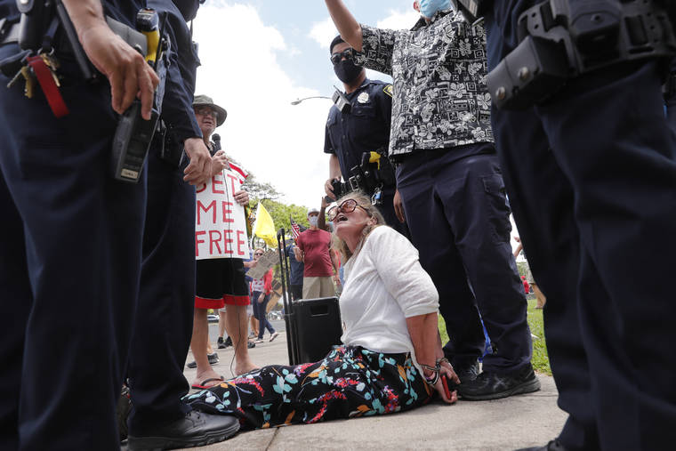 JAMM AQUINO / JAQUINO@STARADVERTISER.COM
                                A protester is arrested by Honolulu police during a rally in support of reopening the state of Hawaii’s businesses and economy today.