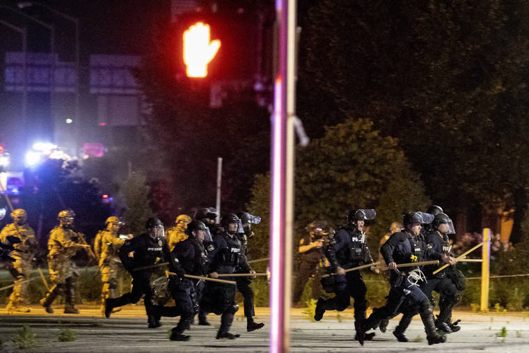 ASSOCIATED PRESS
                                Police and Kentucky National Guard troops chase protesters as they flee toward a fence Sunday in a parking lot at the corner of East Broadway and South Brook Street in downtown Louisville, Kentucky.